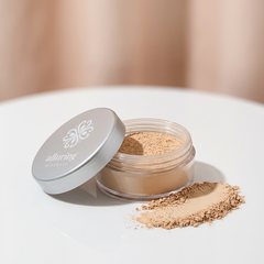 Open container of loose powder with a brand logo on a neutral background