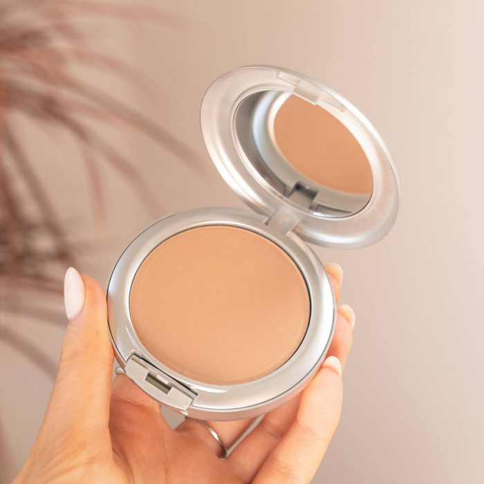 Hand holding an open Alluring Minerals Pressed Mineral Foundation compact with built-in mirror