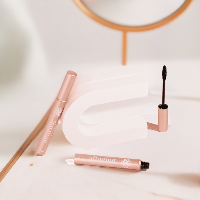 Alluring Minerals Accelerating Mascara in a rose gold tube, styled with the wand beside an arch mirror