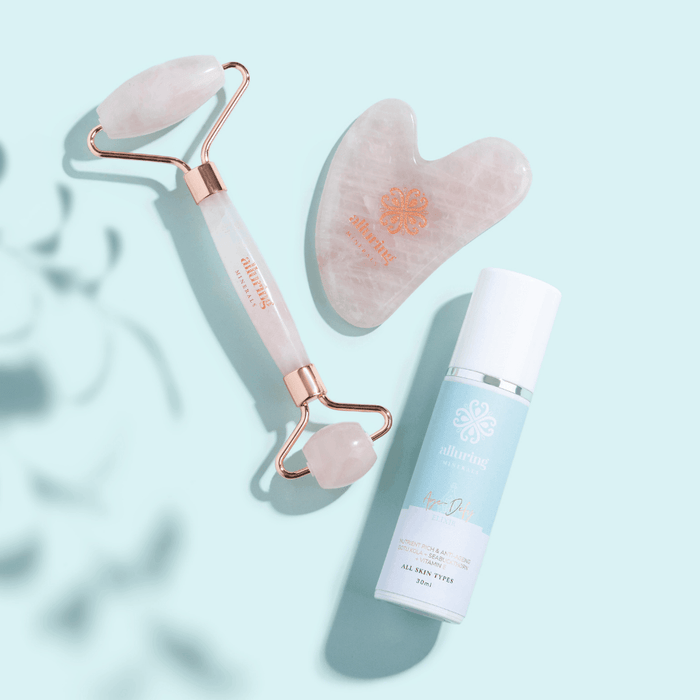 Alluring Minerals rose quartz face roller and gua sha styled with a skincare bottle